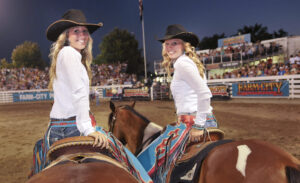 Cowgirls on horseback await entry into rodeo arena